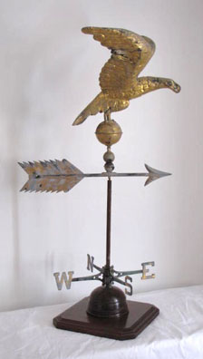 Great Eagle Weathervane in its original gold gilt paint, standing on a ball with pointing arrow, mounted on a custom wooden stand.